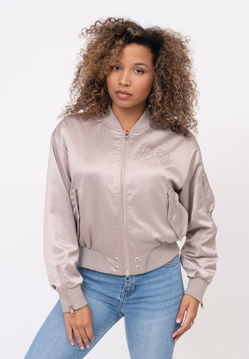Metalen zilveren bomberjack met ribbelboord en -zoom, voorzien van geborduurd ontwerp, met rits afgesloten zakken en een gladde satijnen-textuur.