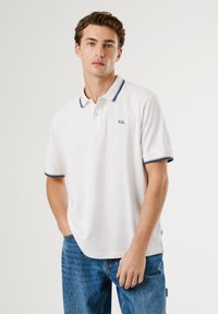 Biely polo tričko s golierom, s modrými akcentmi na manžetách a golieri. Malé logo "PJL" na ľavej hrudi. Bavlnený materiál.