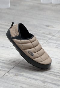 Beige spalvos siuvinėta šlepetė su juodu guminio pado ir užnugario. Ant šono yra The North Face logotipas ir kilpos ant kulno.