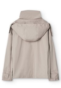 Giacca da pioggia beige chiaro con cappuccio vista da dietro, con maniche lunghe e polsini regolabili, realizzata in un tessuto impermeabile e liscio.