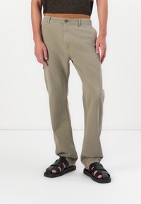 Lichtgroene broek van een katoenmix, met zijzakken en een recht model. Gecombineerd met zwarte strap-sandalen.