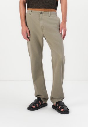 Light green pants made of cotton blend, featuring side pockets and a straight leg design. Paired with black strappy sandals.
