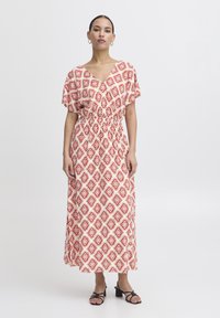 Abito lungo con un motivo geometrico rosso e bianco, caratterizzato da una scollatura a V e maniche corte; il tessuto ha una texture leggera e fluida.