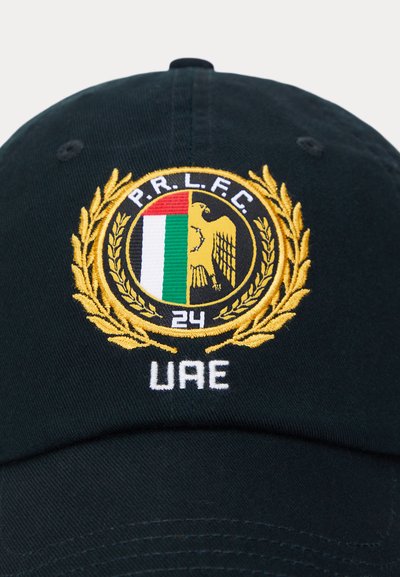 Cappellino da baseball nero con un logo circolare ricamato, decorato con accenti dorati di alloro, strisce verdi, rosse e bianche, e il testo "UAE" in bianco.