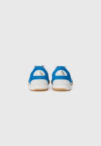 Zapatillas deportivas azules y blancas con una parte superior de malla texturizada, suelas de goma y un acento triangular en el talón. Materiales suaves y transpirables.