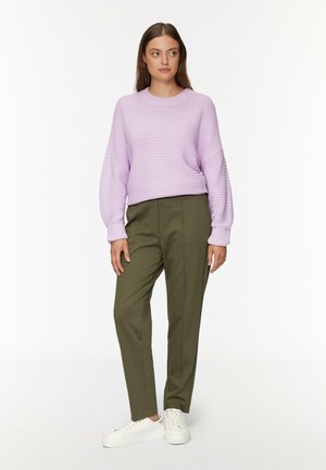 Jasnofioletowy sweter z prążkowanego materiału z szerokimi rękawami, dopasowany z oliwkowymi spodniami i białymi sneakersami. Prosty, nowoczesny outfit.