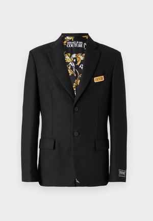 Fekete zakó, két gombbal, felső gallérral és oldalsó zsebekkel. Mintás béléssel, arany és fehér részletekkel. címke a zsebében.