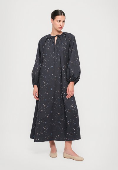 Tummansininen mekko, jossa on pitkät puffihihat, piilotettu nyörikaulus ja kultaisista sekä vaaleansinisistä tähdistä koostuva kuvio.