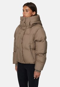 Kurtka puchowa w ziemistym brązie, z wysokim kołnierzem, kieszeniami na zamek i ściągaczami przy mankietach. Gładka tekstura z pikowanymi panelami.