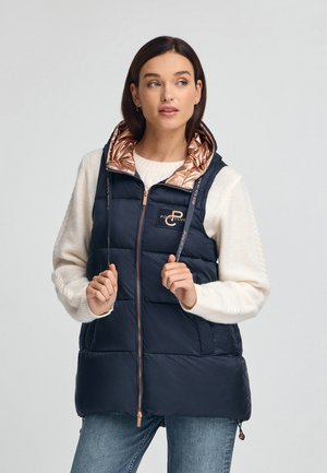 Chaleco acolchado azul marino con capucha acentuada en bronce, cuenta con cierre con cremallera y dos bolsillos delanteros. Diseño acolchado con detalle del logotipo.