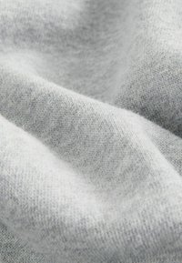 Tejido gris claro que presenta un suave punto texturizado con una superficie lisa y sutiles variaciones de tonalidad.