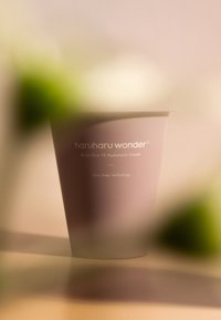 Fioletowy pojemnik na czarny ryż 10% kremu hialuronowego, charakteryzujący się eleganckim designem, wytłoczonym tekstem i minimalistycznym stylem. Rozmyte tło.