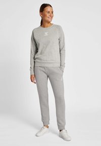 Grey sweatshirt with raglan sleeves and a crew neck, paired with matching grey jogger pants. Both feature a white logo and elastic cuffs.