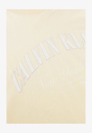 Tissu beige avec texte blanc en relief « CALVIN KLEIN » en grandes lettres, et texte cursif pâle « New York » en dessous.