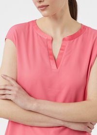 Rosa Kurzarmoberteil mit V-Ausschnitt, aus glattem Stoff gefertigt. Der Kragen ist mit einem satinartigen Besatz versehen, was dem Design eine dezente Note verleiht.