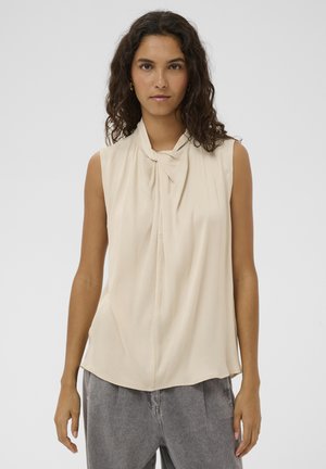 Bluza bej fără mâneci, cu decolteu drapat și nod, textură moale și croială lejeră, combinată cu pantaloni gri cu talie înaltă.