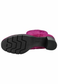 Botín de ante fucsia hasta el tobillo con una suela de goma negra que presenta un patrón de banda de rodadura en zigzag y un tacón bajo para mayor estabilidad.