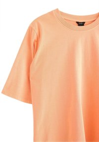  ferskenfarvet bomulds crew neck t-shirt med korte ærmer. Glat tekstur og minimal syning detaljer. Mærket synligt indeni kraven.