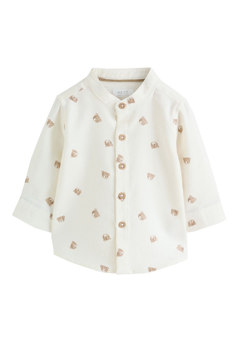 Chemise bébé de couleur crème avec manches longues, imprimée de visages d'ours en peluche marron partout, et cinq boutons en bois sur le devant.