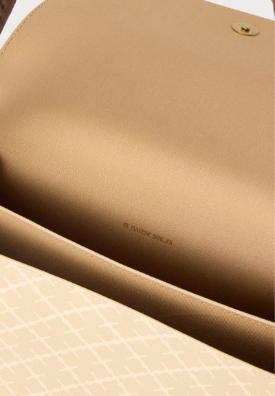 Εσωτερικό μπεζ τσάντας με υφασμάτινη επένδυση, μαγνητικό κούμπωμα και διακριτικό ανάγλυφο κείμενο της μάρκας στο εσωτερικό.