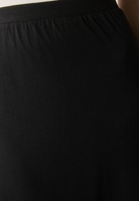 Zwarte rok met een gathered tailleband en een gladde textuur, gemaakt van rekbaar materiaal, wat zorgt voor een aansluitende silhouet.