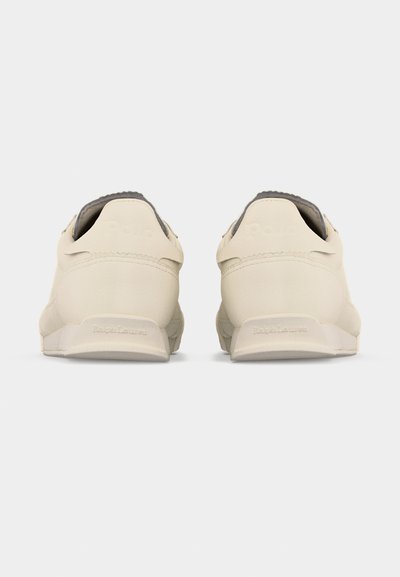 Ζευγάρι κρεμ αθλητικά παπούτσια Polo Ralph Lauren, εμφανιζόμενα από πίσω, σε λευκό φόντο.