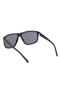 Gafas de sol negras con lentes gris oscuro, marco rectangular y acabado mate suave. Diseño ligero con brazos curvados en negro.