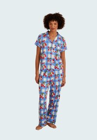Blue checkered pajama set featuring cherry prints, short-sleeve top with pocket, and long pants. Soft fabric with contrasting trim details.