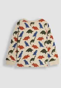 Chemise à manches longues en tissu crème ornée d'impressions de dinosaures multicolores en rouge, bleu et vert. Encolure ronde et poignets côtelés.