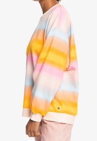 Sudadera de algodón con franjas horizontales en rosa, naranja, azul y amarillo. El diseño incluye un corte relajado y puños acanalados.