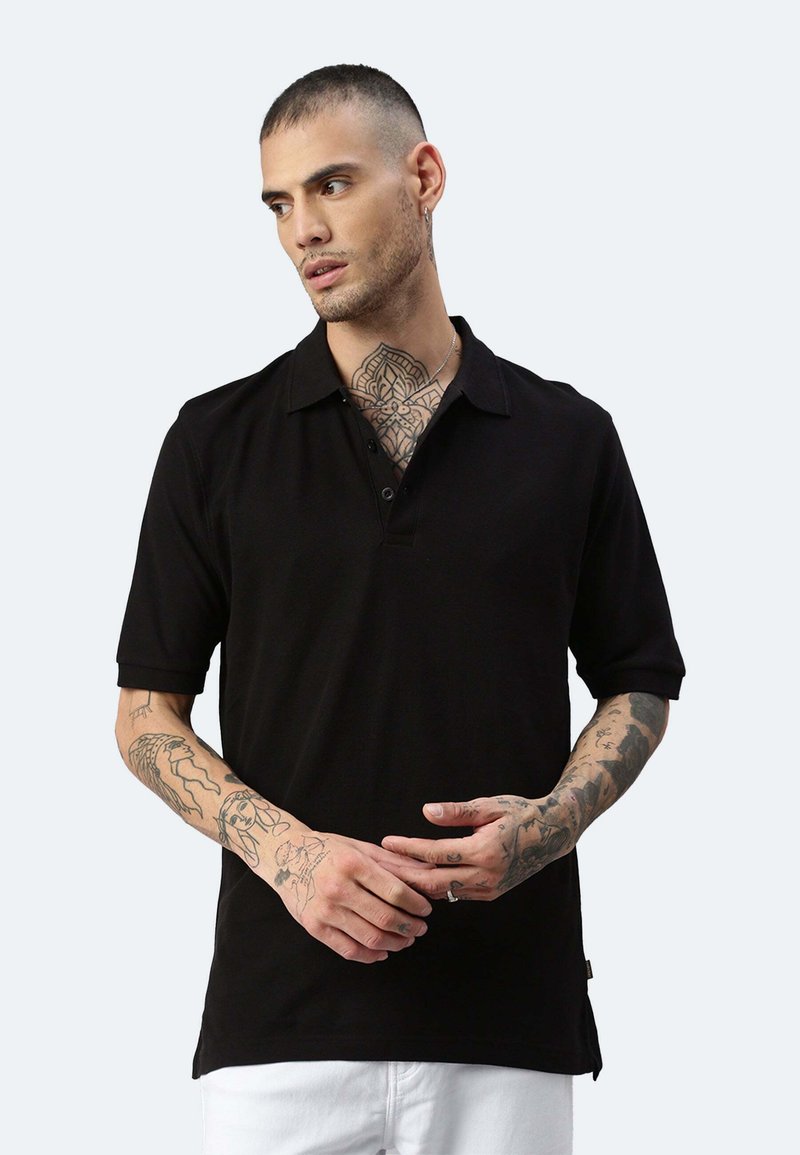 Polo shirt nero a maniche corte con colletto, dotato di bottoni e fondo con spacco laterale. Tessuto dalla consistenza liscia, design aderente.