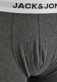 Graue Baumwoll-Boxershorts mit einem weißen elastischen Bund, auf dem "JACK & JONES" in schwarzer Schrift steht. Auffällige Nahtdetails sind überall zu sehen.