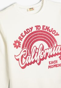Witte sweatshirt van katoen met een ronde hals. Bevat rode glinsterende tekst en graphics, inclusief een regenboog en bloemetjesaccenten.