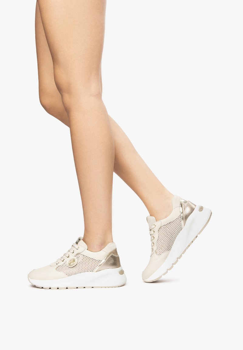 Baskets beiges avec des accents métalliques dorés, des panneaux en mesh et des semelles blanches. Elles disposent de lacets et d'un rembourrage autour de la cheville pour plus de soutien.