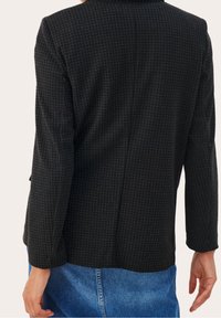 Blazer nero a fantasia con design a scacchi, dotato di maniche lunghe, una vestibilità sartoriale e un orlo diritto, abbinato a una gonna di jeans.