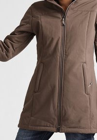 Manteau marron à fermeture éclair avec capuche, doté de deux poches avant et d'une coupe légèrement cintrée, confectionné dans un matériau lisse et texturé.