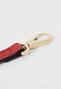 Red leather strap with a gold-toned metal clasp bearing the "Valentino" logo. Features a smooth texture and a shiny finish.