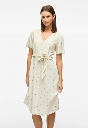 Vestido beige claro con mangas cortas, escote en V, botones en la parte delantera, cinturilla ajustable y un sutil patrón geométrico en azul oscuro y rojo.