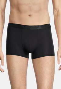 Boxer in colore nero realizzati in un materiale morbido, con una vita morbida e un logo discreto, e un design aderente.
