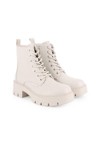 Botas de tobillo de cuero blanco con cordones en la parte delantera, suela gruesa de plataforma, puntera redondeada y tira en la parte trasera. Presentan una superficie texturizada y detalles de costura.