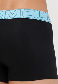 Sorte boxershorts med en lyseblå elastisk livlinje med iøjnefaldende tekst. Materialet ser glat ud med en tætsiddende pasform.