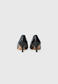 Black high-heeled shoes with a pointed toe and textured croc-embossed leather. Features a slender heel and smooth beige interior.