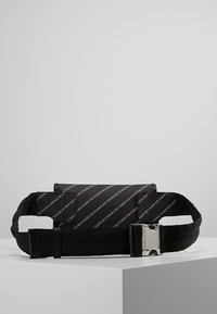 Borsa in tessuto nero con motivi a logo stampati in diagonale, tracolla regolabile e fibbia in metallo argentato. Forma piatta e rettangolare con una superficie liscia.
