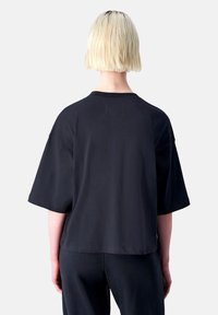 Schwarzes, übergroßes T-Shirt mit kurzen Ärmeln, Rückansicht. Weicher Stoff, runder Ausschnitt, Nahtdetails und lockere Passform.