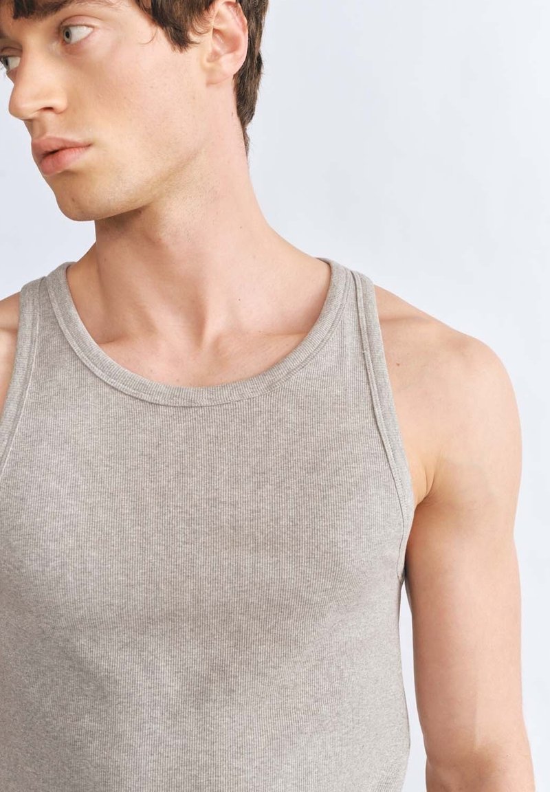 Szary top na ramiączkach z prążkowanej tkaniny, szerokimi otworami na ramionach i zaokrąglonym dekoltem, o dopasowanym kroju i miękkim składzie materiału.