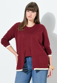 Burgundy kardar som är tillverkad av stickad tyg, har långa ärmar, två framfickor och kontrasterande krämfärgade muddar och nederkant. Matchas med en tillhörande topp.