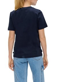 T-shirt en coton bleu marine à manches courtes, coupe droite et détails de couture au dos. Porté avec un jean cargo bleu clair.