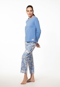 Lichtblauwe lange mouwen top van zachte stof. Bijpassende geprinte broek met een blauw-wit abstract ontwerp en een cropped fit.