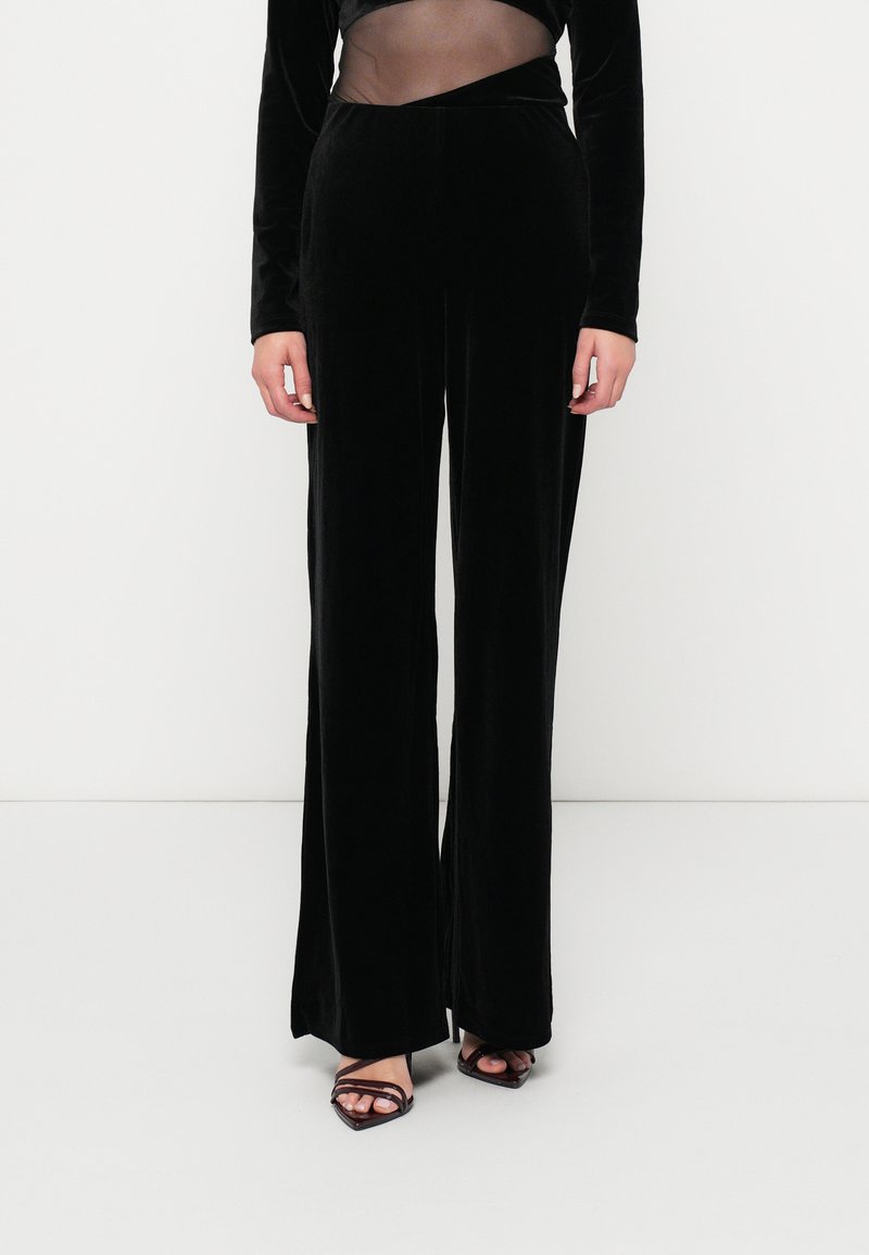 Μαύρο βελούδινο παντελόνι με φάρδος, με ομαλή υφή, που διαθέτει ψηλή μέση και κομψό, ραμμένο σχέδιο. Φοριέται με μαύρες ψάθινες γόβες.