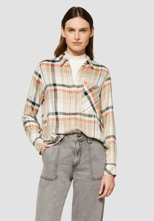 Gevlekt button-up shirt in perzik, beige en groene tinten met een enkele borstzak; gecombineerd met grijze high-waisted jeans.